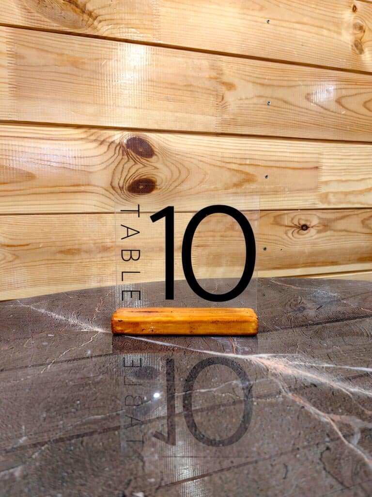 table number ten clear acrylic sign on restaurant marble tabletop. vertical. Customized plexiglass in Bozeman Montana